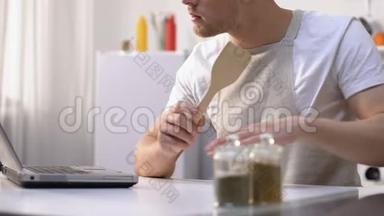 饥肠辘辘的男人在笔记本电脑上看<strong>菜谱</strong>，做业余搅拌配料